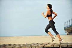 Woman running on a beach boardwalk demonstrating repetitive motion activity
