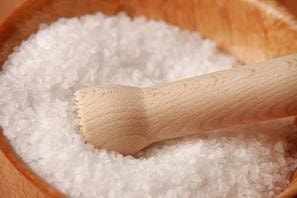 Coarse white sea salt in a wooden bowl with a wooden scoop